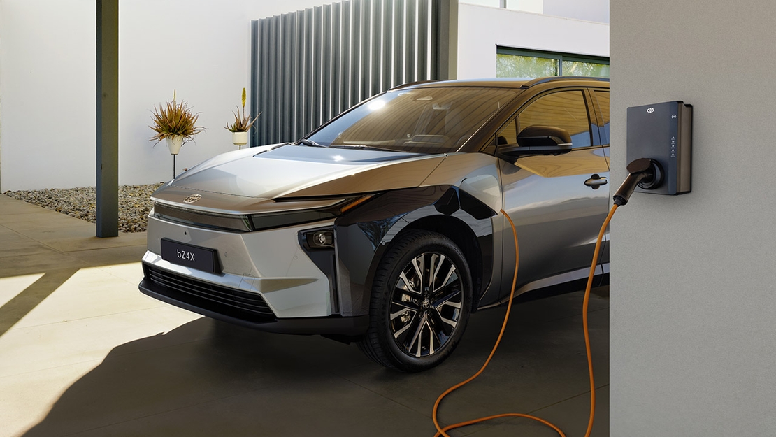 Toyota-bZ4X-driekwart-voorzijde-aan-oplader-achter-muur